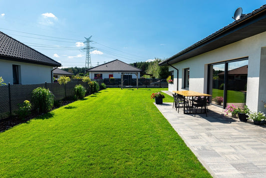 Beautiful garden with green grass, visible terrace table and house in beautiful summer weather.
